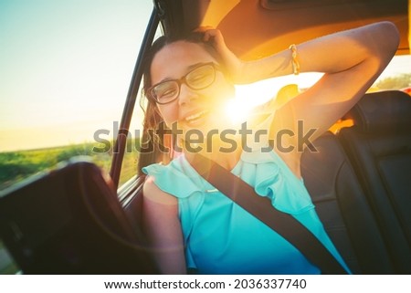 Holidays and tourism concept - smiling teenage girl brunette wearing glasses taking selfie picture with smartphone camera in car