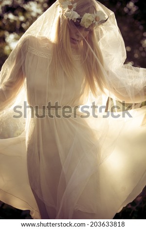 beautiful blonde woman with wreath of flowers and white veil summer portrait outdoor