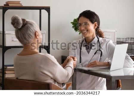 Older patient feeling gratitude to happy GP doctor, shaking hand of young optimistic therapist at appointment in office, thanking for medic care, medical help, therapy, support. Elderly healthcare Royalty-Free Stock Photo #2036344217