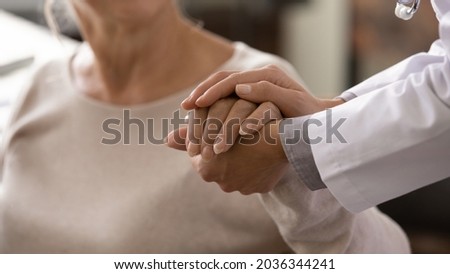 Female doctor in white coat holding hand of senior patient, giving help, comfort, psychological support, empathy at appointment. Elderly medic care, geriatric healthcare concept. Close up Royalty-Free Stock Photo #2036344241