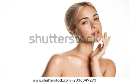Beauty skin. Head and shoulders of blond woman model, touching glowing, hydrated facial skin, apply toner, skin cream or lotion for healthy look, after shower portrait, white background. Royalty-Free Stock Photo #2036349293