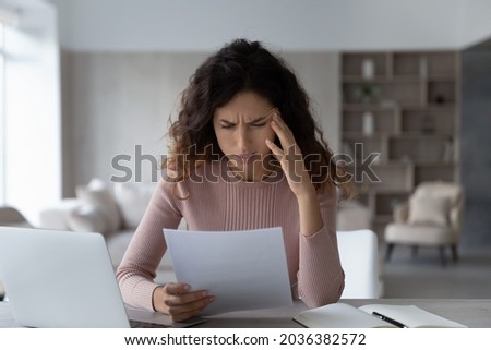 Unhappy depressed young latin woman reading bank loan rejection notification, feeling stressed of getting bad news in paper correspondence, holding bankruptcy notice, having financial problems. Royalty-Free Stock Photo #2036382572