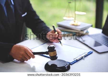 Judgment hammer on a wooden table and a male lawyer or judge works with courtroom style agreements. concept of justice and law