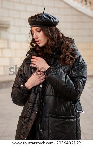 stylish woman posing in winter autumn fashion trend black puffer coat and leather hat beret in old beautiful street Royalty-Free Stock Photo #2036402129