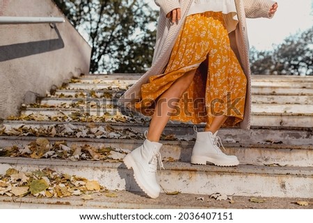 close-up legs in stylish white boots footwear of young woman in yellow printed dress on sunny autumn day having fun in street wearing fashion trend outfit Royalty-Free Stock Photo #2036407151