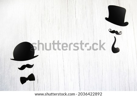 Fake moustache,tie bow and hat on a white wooden background.International Mens's Day and Fathers Day concept Flat lay, top view, copy space space for text