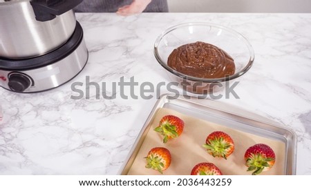 Step by step. Dipping organic strawberries into melted chocolate.