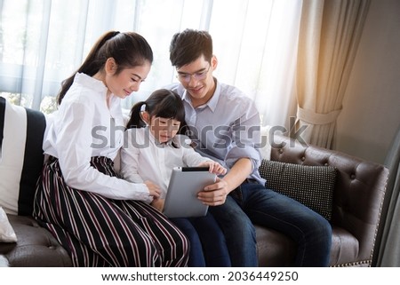 Father and mother Teaching children use tablet to do their homework at home, Asian family is happy concept.
