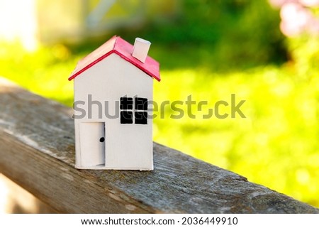 Miniature white toy model house in wooden background near green backdrop. Eco Village, abstract environmental background. Real estate mortgage property insurance dream home ecology concept