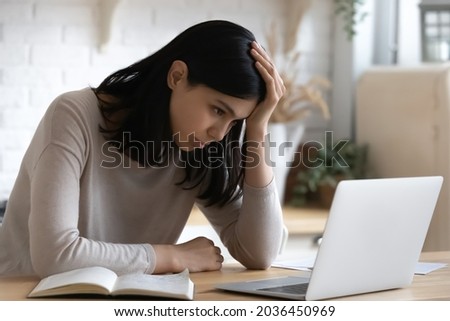 Confused unhappy young korean asian woman looking at laptop screen, feeling dissatisfied reading email with bad news, stuck with difficult working task, thinking of problem solution at home office. Royalty-Free Stock Photo #2036450969