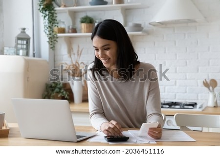 Happy young asian korean woman managing household budget, calculating bills, paying online for services taxes in e-banking application, planning future investment, feeling satisfied with enough money. Royalty-Free Stock Photo #2036451116