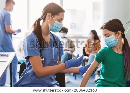 Female doctor holding syringe making covid 19 vaccination injection dose in shoulder of little patient. Flu influenza vaccine clinical trials concept, corona virus treatment side effect, inoculation Royalty-Free Stock Photo #2036482163