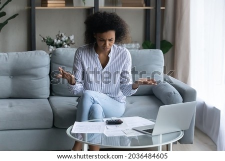 Bank documents do not balance. Concerned afro american female review financial papers at home office dissatisfied with mistake bad result. Confused young black woman think on unexpected debt problem Royalty-Free Stock Photo #2036484605