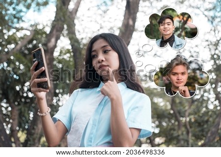 A young asian woman using a dating app deciding who to meet up with. Thought bubbles show two handsome men. Royalty-Free Stock Photo #2036498336