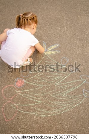 chalk pattern on asphalt. A little cute girl draws a Christmas tree for the new year and Christmas with colored crayons. Art therapy. Green spruce, place for text