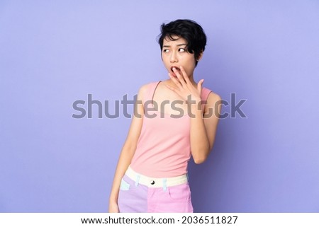 Young Vietnamese woman with short hair over isolated purple background yawning and covering wide open mouth with hand