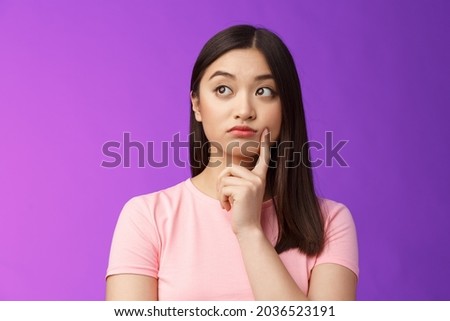 Close-up thoughtful cute asian girl dreamy standing purple background, touch cheek, turn left, thinking, doubting how act, wondering information, contemplating view from window Royalty-Free Stock Photo #2036523191