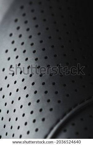 Perforated material made of black imitation leather in full screen. Close-up