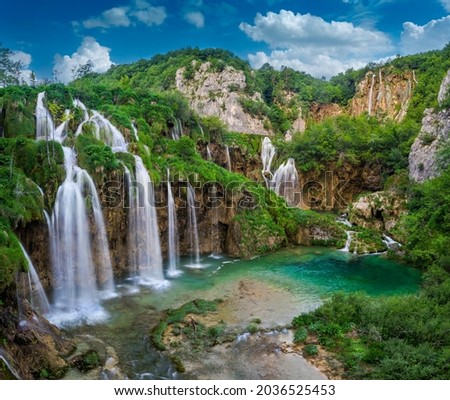Plitvice, Croatia - Beautiful waterfalls of Plitvice Lakes (Plitvička jezera) in Plitvice National Park on a bright summer day with blue sky and clouds and green foliage and turquise water Royalty-Free Stock Photo #2036525453