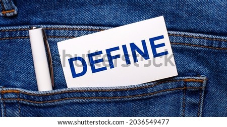 The back pocket of blue jeans contains a white pen and a white card with the text DEFINE