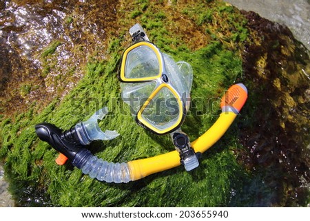 Beach sea mask and snorkel lying on rock. Sea and waves background.