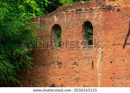 Old red brick fortress wall with windows and greens