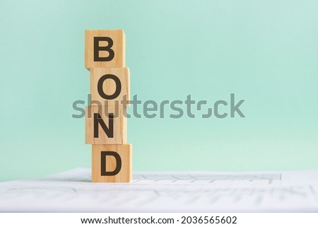 word BOND with wood building blocks, light Blue background. document with numbers on background, business concept. space for text in right. front view