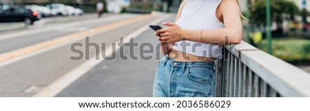 Unrecognizable young woman outdoor using smartphone - advertising copyspace cropped banner