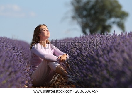 Relaxed woman breathing fresh air sitting in a lavender field a sunny day Royalty-Free Stock Photo #2036596469