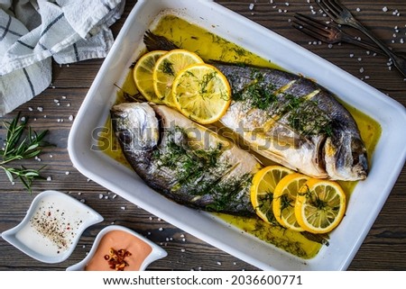 Roast sea bream  in cooking pan on wooden table
