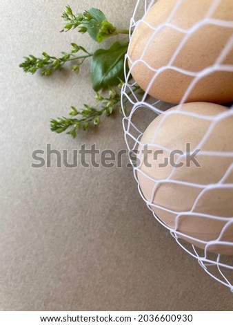 Chicken eggs in a string bag with plants, grass, brown background. Brown eggs in cardboard tray for eggs. Eggs for Easter. Background for cafes, restaurants, fast food outlet. Craft background.