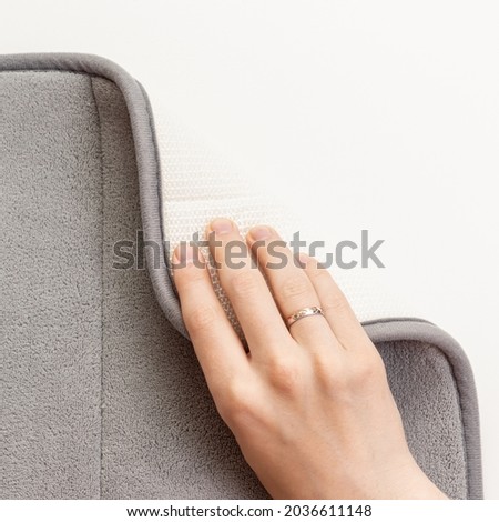 Man bends edge of gray mat for bathroom. Mat material and texture. Non-slip coating Royalty-Free Stock Photo #2036611148