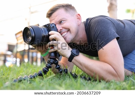 Young male photographer takes pictures on tripod in street closeup