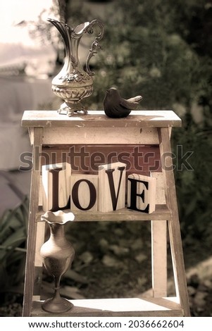 The words of love collected with vintage vases and a bird on a ladder in the garden