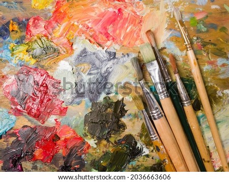 Artist's palette. Oil art paints extruded onto a wooden palette. Tubes and brushes lie on a colorful board