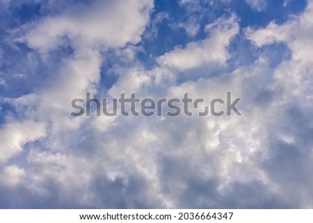blue sky background with cumulus white clouds and looming storm clouds.