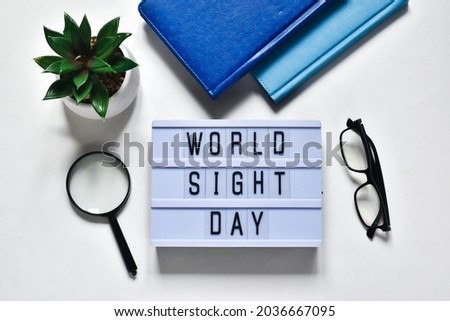 Glasses that correct eyesight, magnifying glass, notepads, green plant and light box with text WOLD SIGHT DAY on a white background. Flat lay. Holiday concept. Royalty-Free Stock Photo #2036667095