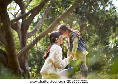 young asian mother and daughter enjoying a good time outdoors in city park Royalty-Free Stock Photo #2036667221
