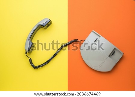 Top view of a retro phone with the handset off on a yellow and orange background. Retro means of communication. Flat lay.