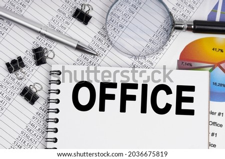 Business and economics concept. On the table is a magnifying glass, reports, a pen and a notebook with the inscription - OFFICE