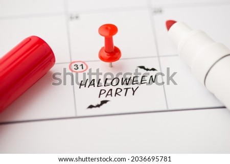 Overhead photo of label date 31 october with inscription halloween party two bats red pin and marker isolated on the calendar background