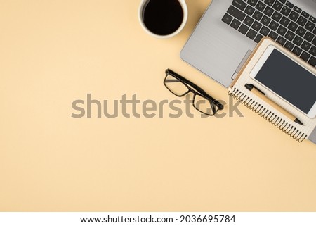 Above photo of grey laptop cup of coffee notepad with pen glasses and phone isolated on the beige backdrop with blank space