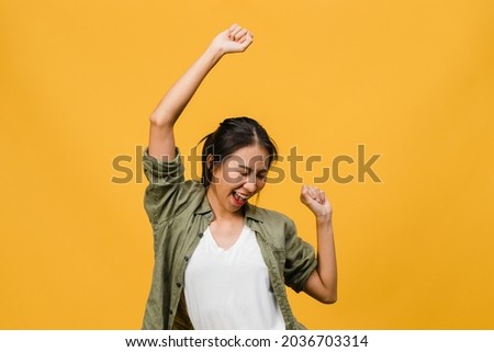 Young Asia lady with positive expression, joyful and exciting, dressed in casual cloth over yellow background with empty space. Happy adorable glad woman rejoices success. Facial expression concept. Royalty-Free Stock Photo #2036703314