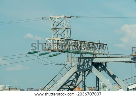 Electric pole against the background of the arch of the railway bridge. Power lines along railway tracks. Power supply of railway transport facilities.