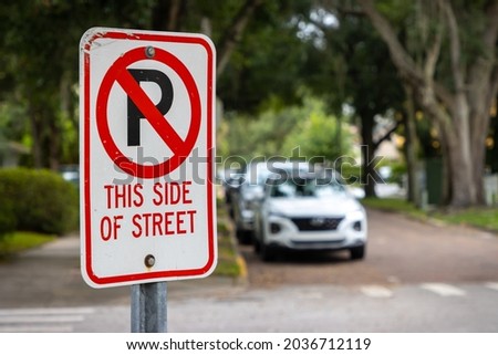 No parking sign with cars on side of city street