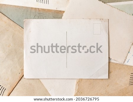 Vintage postcard on old grunge paper and envelopes background. Vintage background from old post cards.   Royalty-Free Stock Photo #2036726795