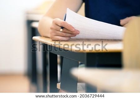 High school or university student holding pencil writing on paper answer sheet. Final exam concept.