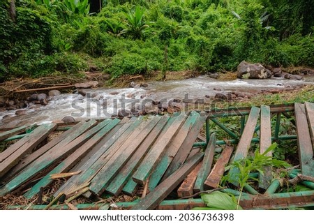 dangerous wooden bridge in mountain was ruined from flash flood after heavy rain and storm. debris flow destroyed a pathway. disaster from flood and water in forest. natural for hiking in Jungle