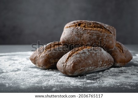 Rustic breakfast settings, freshly baked rye bread buns on a stone gray table.