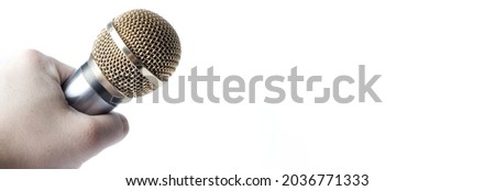 A man's hand holds a microphone on a white background with a gold-plated tip. Copy Space.